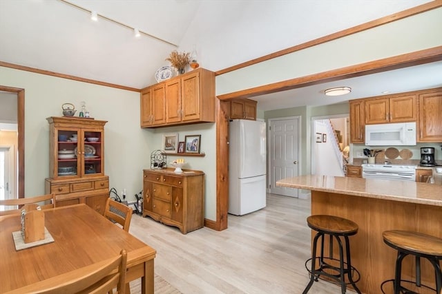 kitchen with light stone countertops, white appliances, brown cabinets, and lofted ceiling