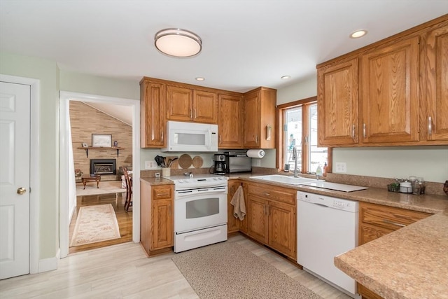 kitchen featuring light countertops, white appliances, a sink, and brown cabinets