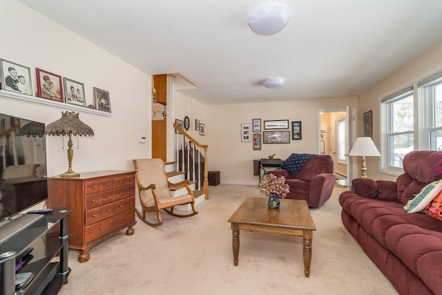 living area with light colored carpet and stairs