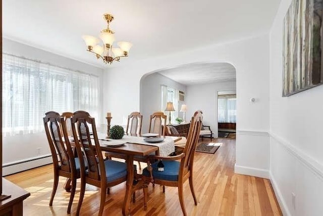 dining room featuring a baseboard radiator, arched walkways, a notable chandelier, and light wood-style flooring