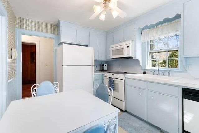 kitchen with white appliances, a ceiling fan, a sink, light countertops, and white cabinets