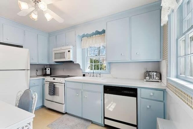 kitchen with a sink, white appliances, a ceiling fan, and light countertops