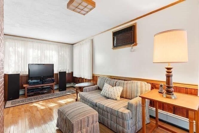 living area featuring a wall mounted air conditioner, a baseboard radiator, hardwood / wood-style floors, and crown molding