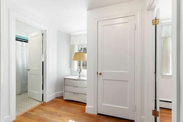 hallway with light wood-style floors and a baseboard radiator