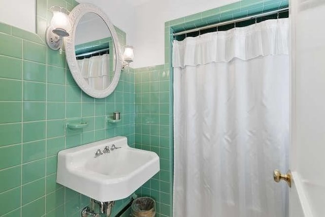 full bathroom featuring curtained shower, tile walls, and a sink