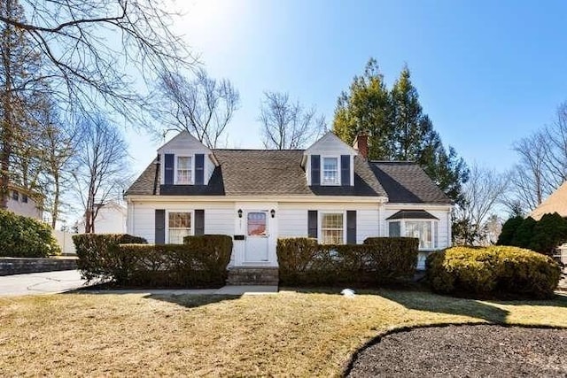 new england style home with entry steps and a front lawn