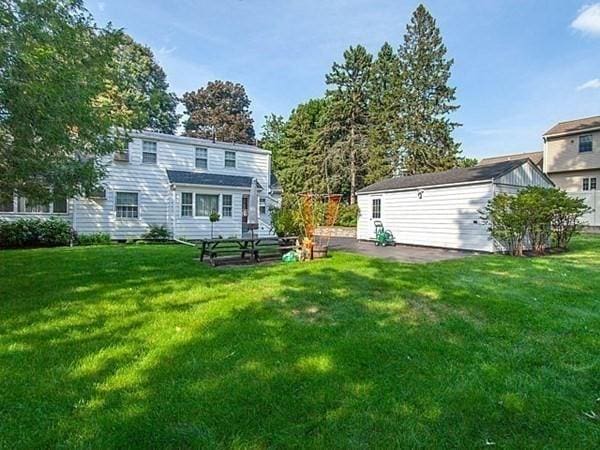 back of property featuring a lawn and an outdoor structure