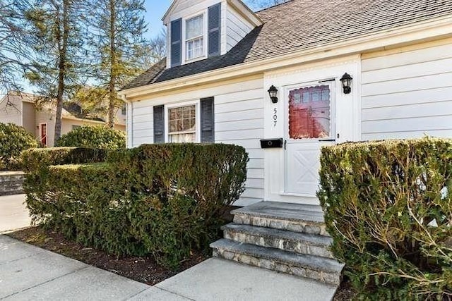 property entrance featuring a shingled roof