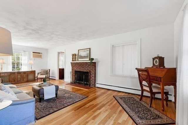 living area with a fireplace, wood finished floors, a wall mounted air conditioner, and a baseboard radiator