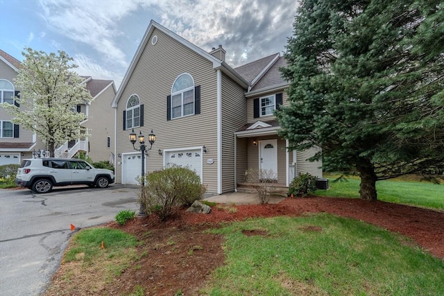 view of front facade with a chimney, central air condition unit, aphalt driveway, and a garage
