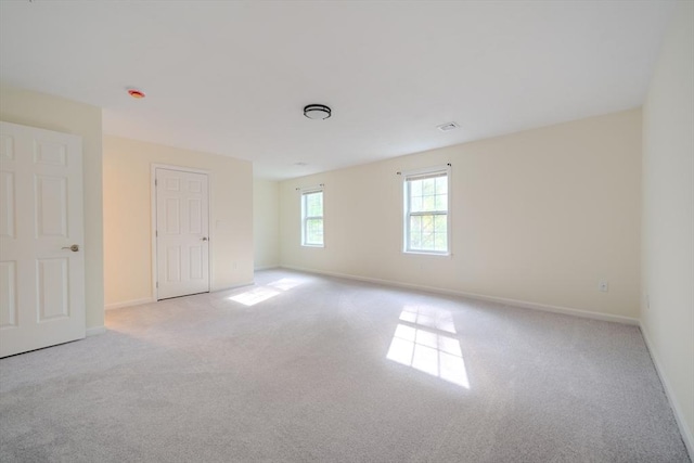 empty room featuring baseboards, light carpet, and visible vents
