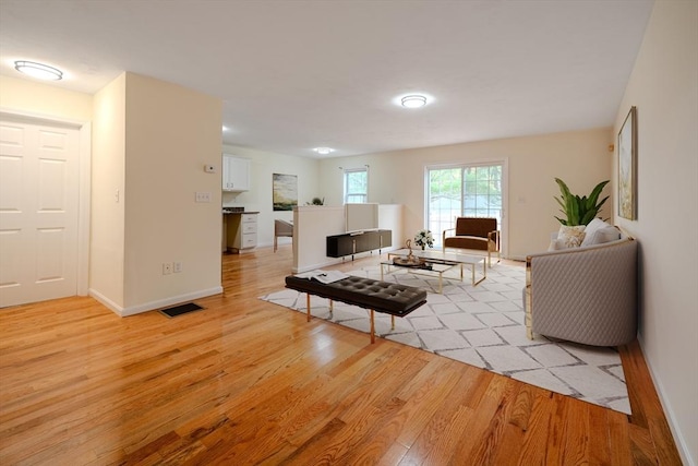 living room with baseboards, visible vents, and light wood-style floors