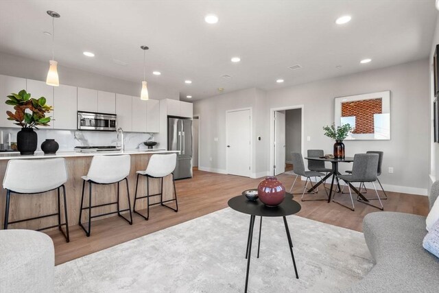 kitchen with decorative light fixtures, stainless steel appliances, light countertops, white cabinets, and modern cabinets