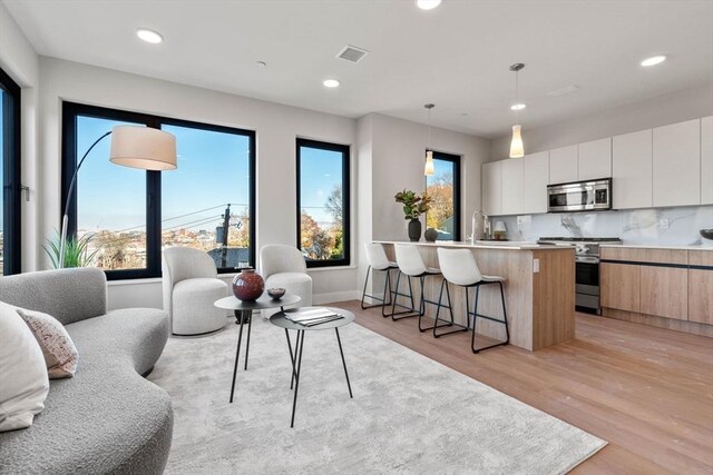 kitchen with white cabinets, modern cabinets, appliances with stainless steel finishes, decorative light fixtures, and light countertops