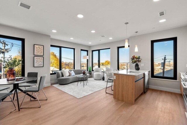 interior space with a sink, a kitchen breakfast bar, open floor plan, light countertops, and pendant lighting