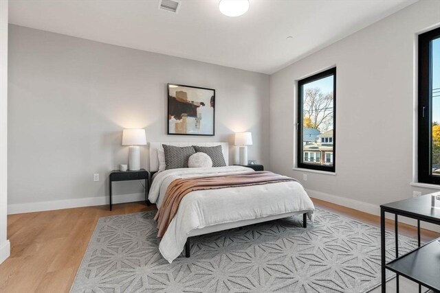 bedroom with light wood-style floors, visible vents, and baseboards