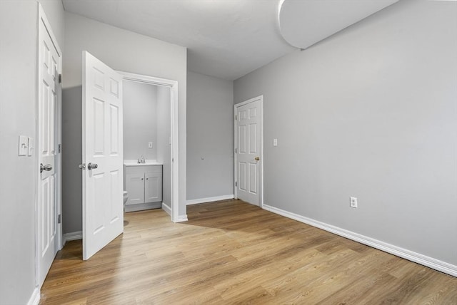 unfurnished bedroom with ensuite bath and light hardwood / wood-style flooring