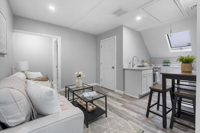 living room with lofted ceiling, sink, and light hardwood / wood-style floors