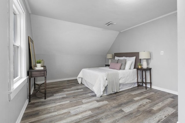 bedroom featuring ornamental molding, lofted ceiling, and hardwood / wood-style floors