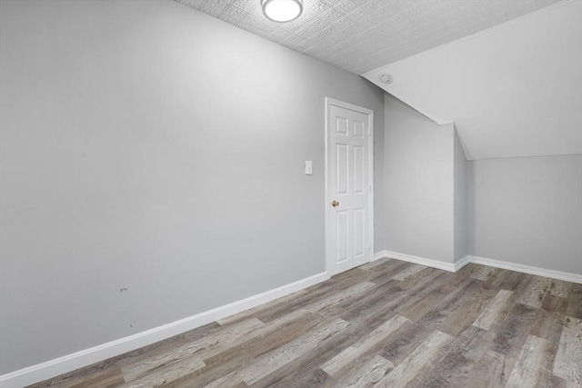 additional living space featuring lofted ceiling and light wood-type flooring