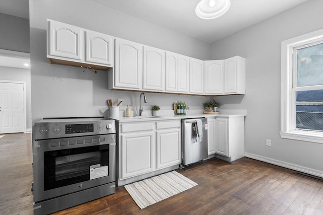 kitchen featuring dark hardwood / wood-style flooring, sink, stainless steel appliances, and white cabinets