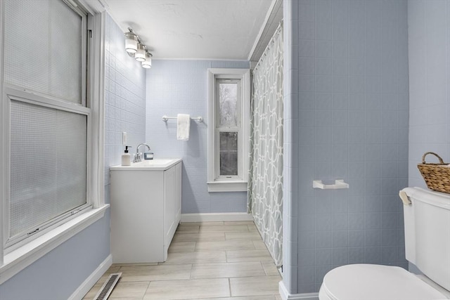 bathroom featuring vanity, tile walls, and toilet