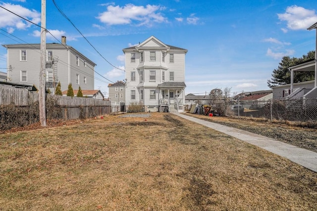 rear view of house with fence and a lawn