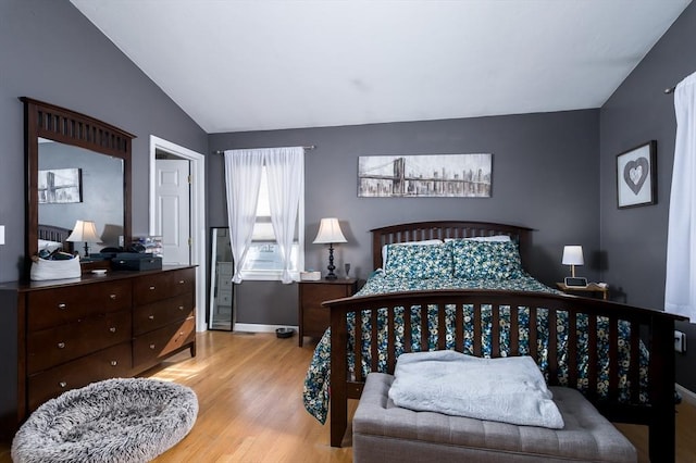 bedroom with wood finished floors, lofted ceiling, and baseboards