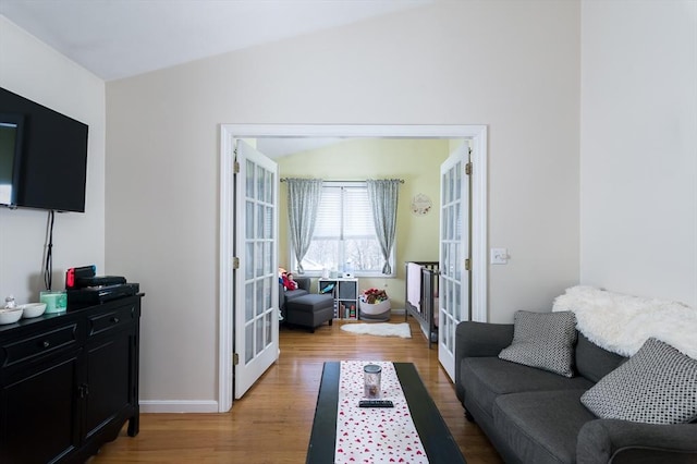 living room featuring french doors, light wood finished floors, vaulted ceiling, and baseboards