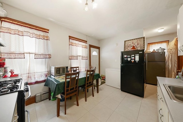 562 Broadway, Everett, MA 02149 - kitchen featuring freestanding refrigerator, range with gas cooktop, a baseboard heating unit, and light countertops