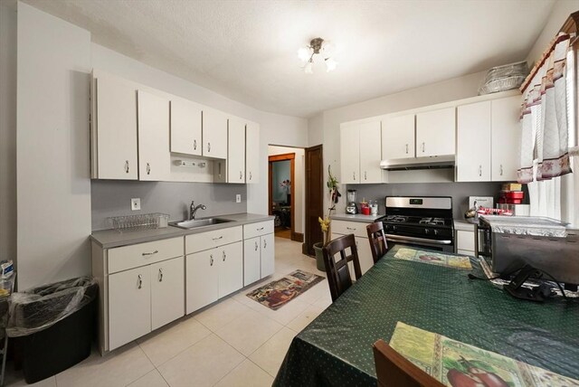 562 Broadway, Everett, MA 02149 - kitchen featuring stainless steel gas stove, under cabinet range hood, white cabinetry, and light tile patterned flooring