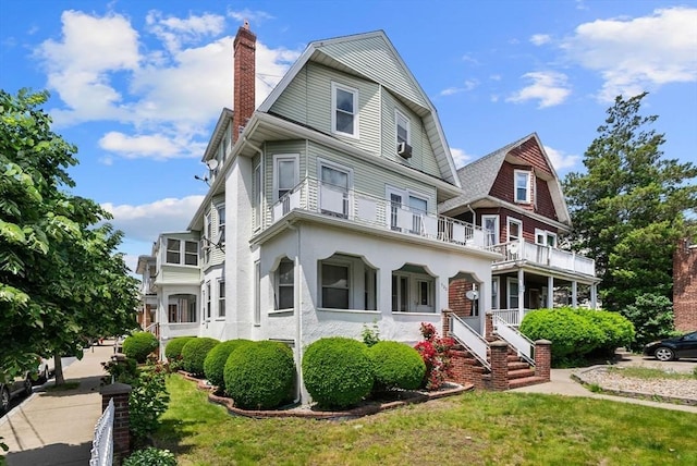 562 Broadway, Everett, MA 02149 - view of front of home featuring a chimney, a balcony, a front lawn, and a gambrel roof