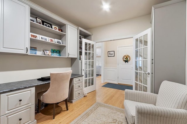 home office with french doors, built in desk, and light hardwood / wood-style floors