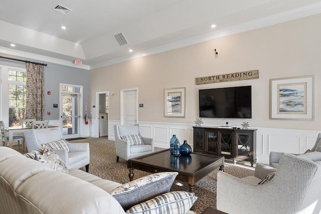 carpeted living room with a tray ceiling and crown molding