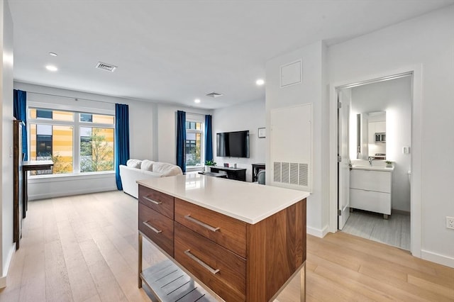 7 Lisbon St Unit 201, Boston, MA 02128 - kitchen featuring brown cabinets, light wood-style flooring, open floor plan, light countertops, and stainless steel microwave