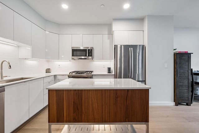 7 Lisbon St Unit 201, Boston, MA 02128 - kitchen featuring stainless steel appliances, modern cabinets, white cabinetry, backsplash, and a kitchen island