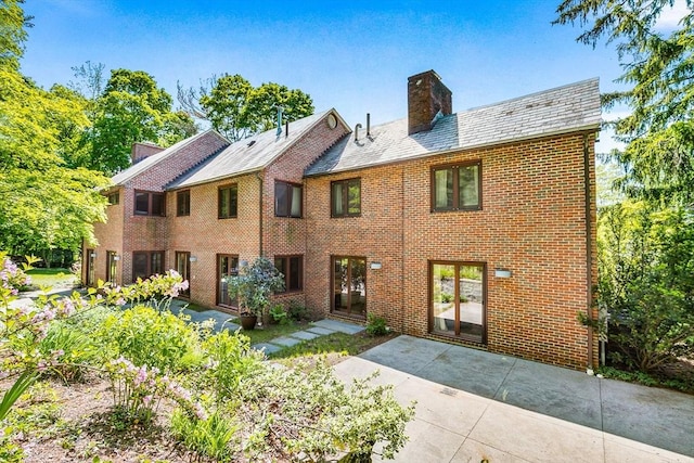 34 Lagrange St, Brookline, MA 02467 - view of front of home with a chimney, a patio, brick siding, and a high end roof
