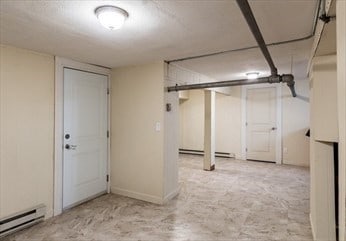 basement with a baseboard radiator and light colored carpet