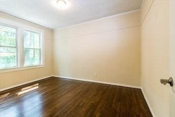 unfurnished room with ornamental molding, dark wood-type flooring, and baseboards