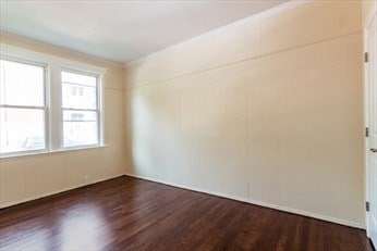 spare room with dark hardwood / wood-style flooring and crown molding