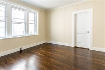 spare room featuring crown molding and dark hardwood / wood-style flooring