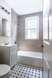 full bathroom featuring tiled shower / bath, vanity, and toilet