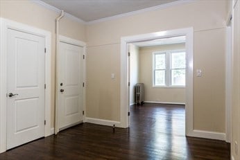 interior space featuring ornamental molding, radiator heating unit, and dark hardwood / wood-style flooring