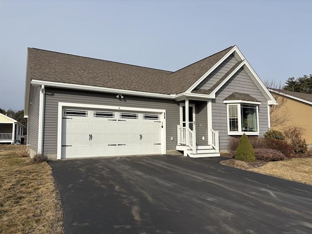 ranch-style home with a garage, driveway, and roof with shingles