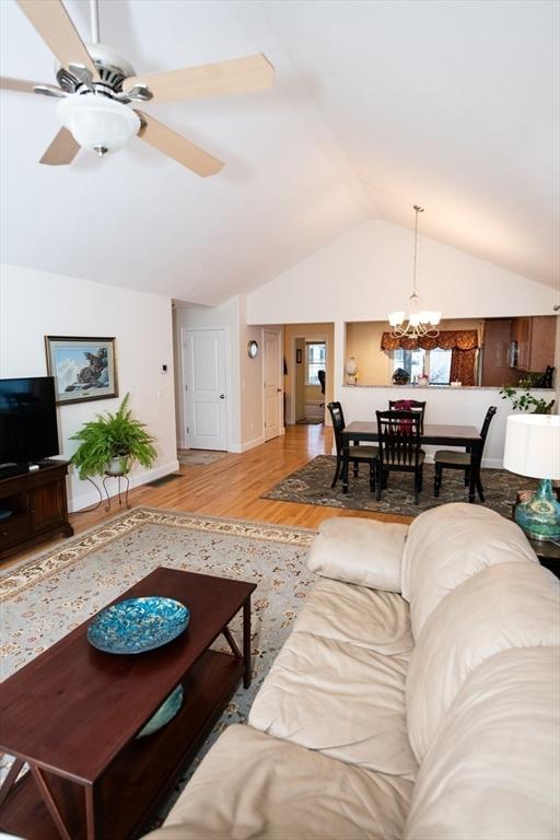 living room with lofted ceiling, wood finished floors, and ceiling fan with notable chandelier