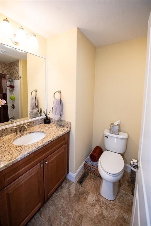 bathroom with vanity, curtained shower, toilet, and baseboards