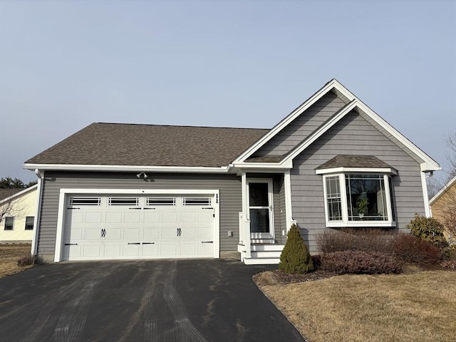 ranch-style house with aphalt driveway, an attached garage, and roof with shingles