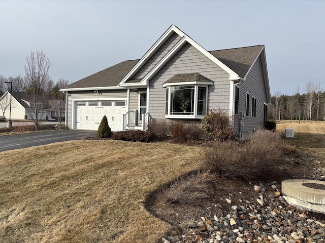 single story home with aphalt driveway, a garage, and a front lawn