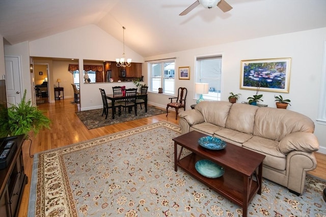 living room featuring ceiling fan with notable chandelier, baseboards, lofted ceiling, and wood finished floors