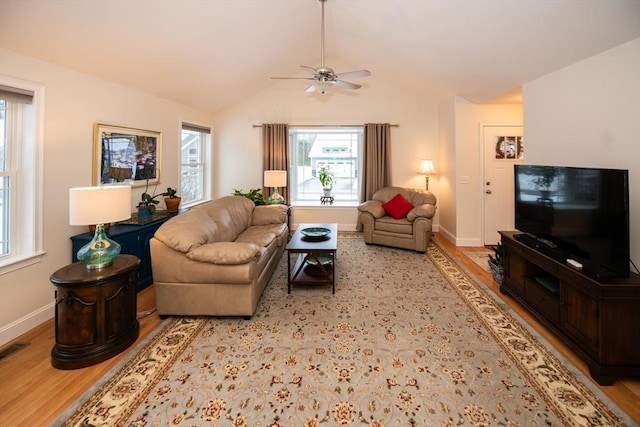 living area featuring visible vents, wood finished floors, baseboards, ceiling fan, and vaulted ceiling